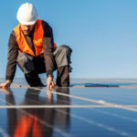 A worker installing solar panels on the roof.